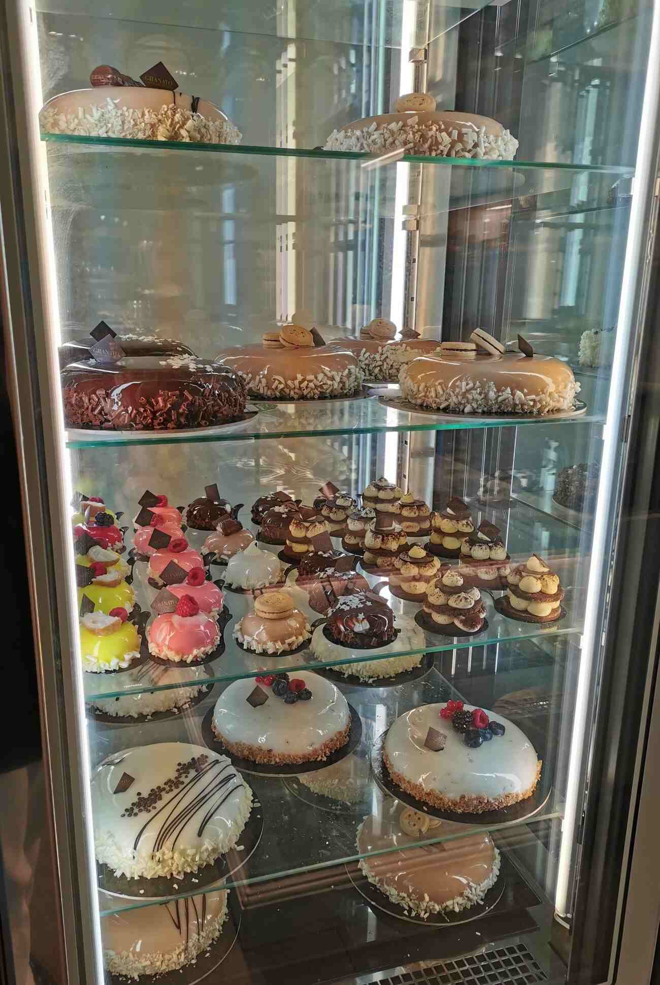 Kuchenvitrine bestückt mit kleinere und größere runde Kuchen