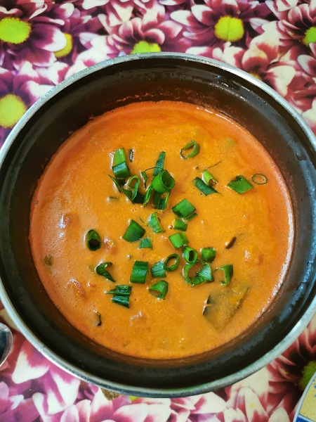 Kiribati-Tomate-Kokos-Suppe im Topf, dekoriert mit Jungzwiebeln